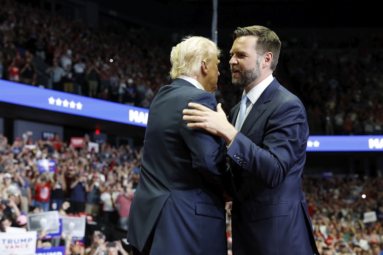 J.D. Vance clasps a hand on Donald Trump's shoulder, in embrace, at the RNC. He is saying something to Trump.