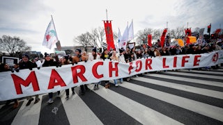 Dozens of protesters walk down the streets of D.C. and hold a large banner that reads "March for Life."