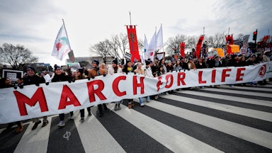 Dozens of protesters walk down the streets of D.C. and hold a large banner that reads "March for Life."