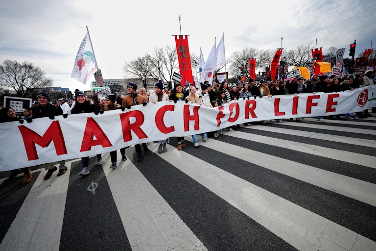 Dozens of protesters walk down the streets of D.C. and hold a large banner that reads "March for Life."