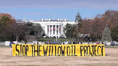 Demonstrators hold up a yellow banner reading "Stop the Willow Oil Project."