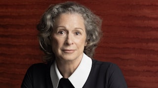 Heiress Abigail Disney, dressed elegantly in black, photographed sitting in front of a red contemporary art work at her dining room table in her home in New York City.
