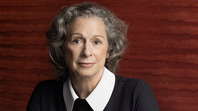 Heiress Abigail Disney, dressed elegantly in black, photographed sitting in front of a red contemporary art work at her dining room table in her home in New York City.