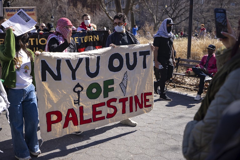 Students hold a large banner reading "NYU Out Of Palestine."