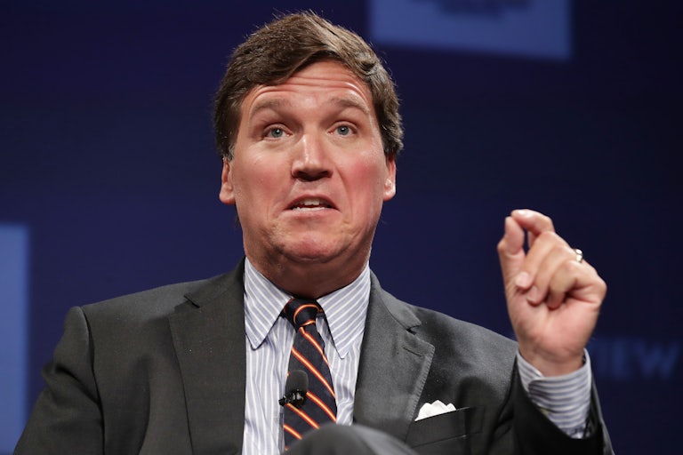 Fox News host Tucker Carlson gesticulates while speaking at an event.