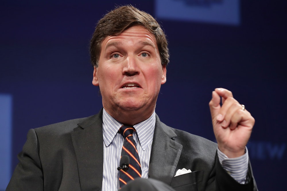 Fox News host Tucker Carlson gesticulates while speaking at an event.