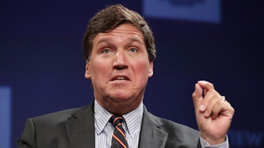 Fox News host Tucker Carlson gesticulates while speaking at an event.
