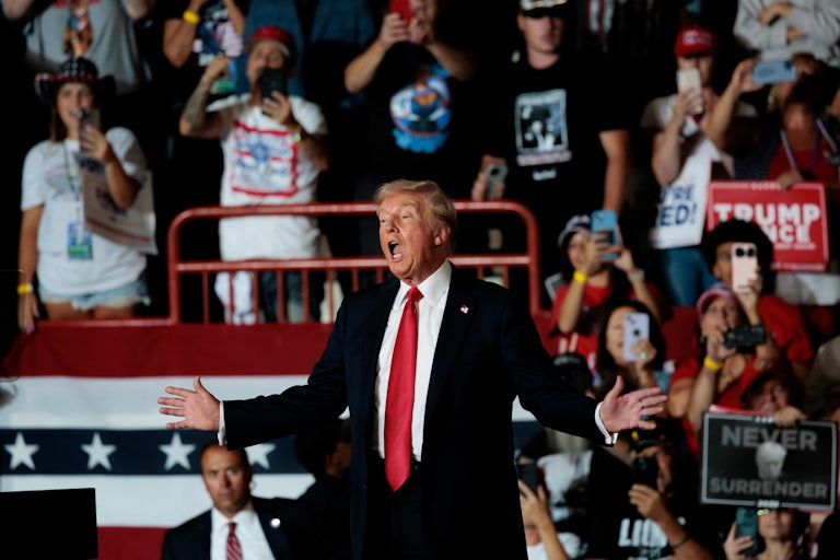 Donald Trump holds his arms out while speaking at a campaign rally
