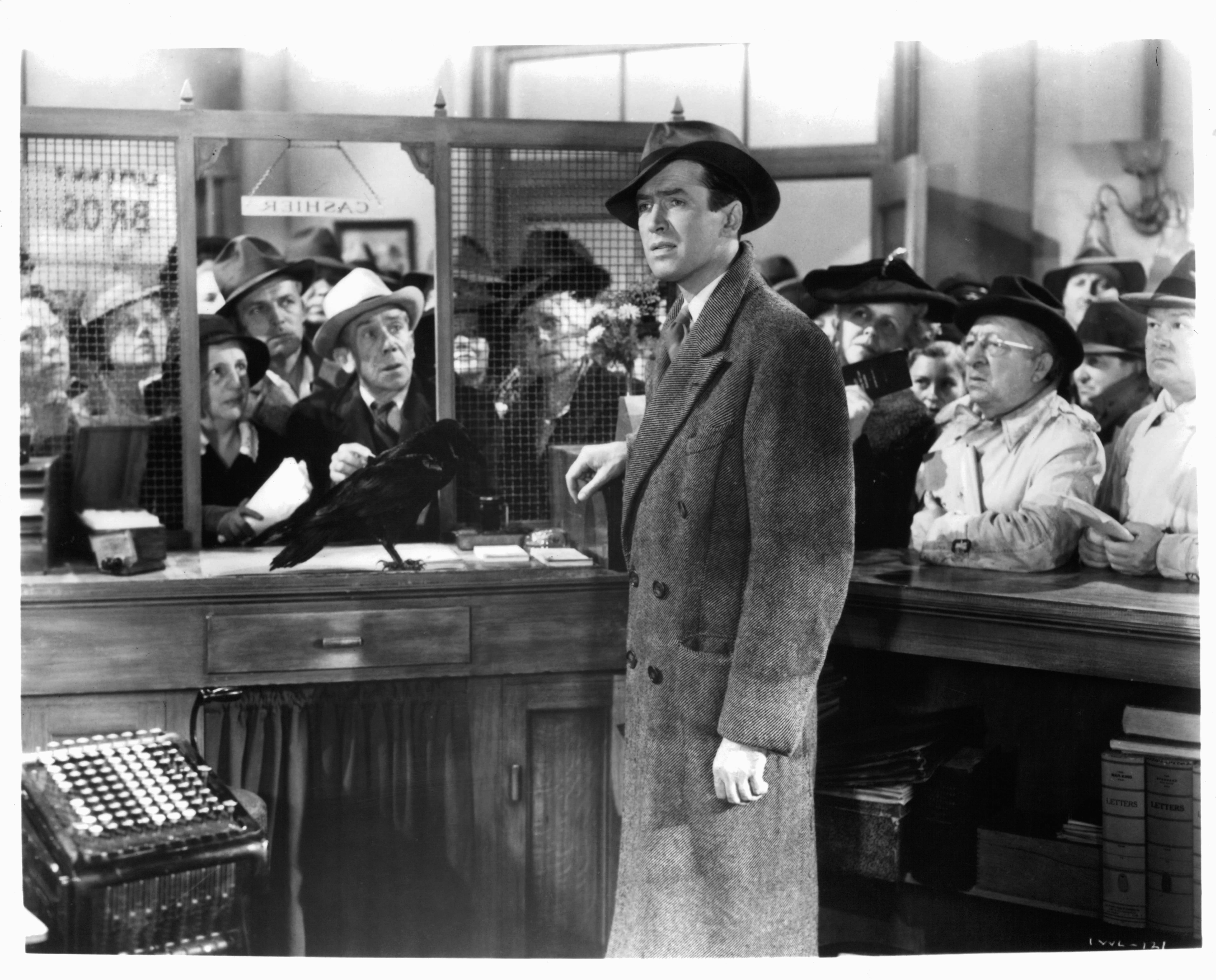 James Stewart standing in the cashier cubicle of a bank in a scene from the film 'It's A Wonderful Life', 1946. 