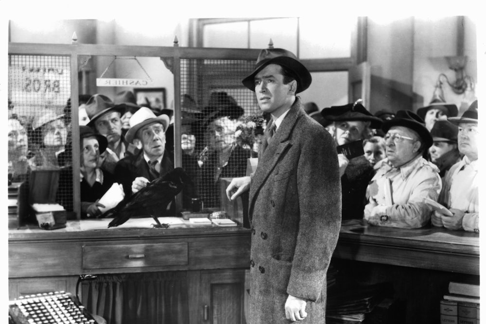 James Stewart standing in the cashier cubicle of a bank in a scene from the film 'It's A Wonderful Life', 1946.