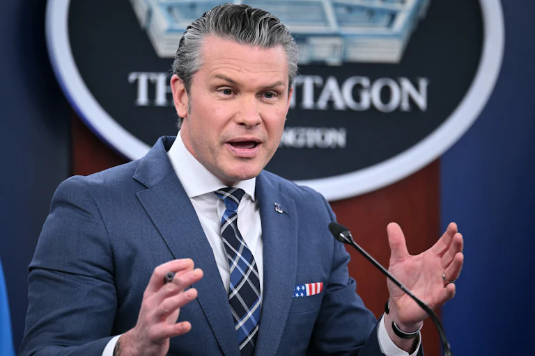 Defense Secretary Pete Hegseth gestures while speaking at a podium