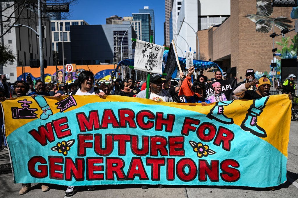 Protesters hold a banner reading "We March for Future Generations."