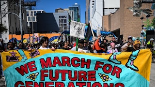 Protesters hold a banner reading "We March for Future Generations."