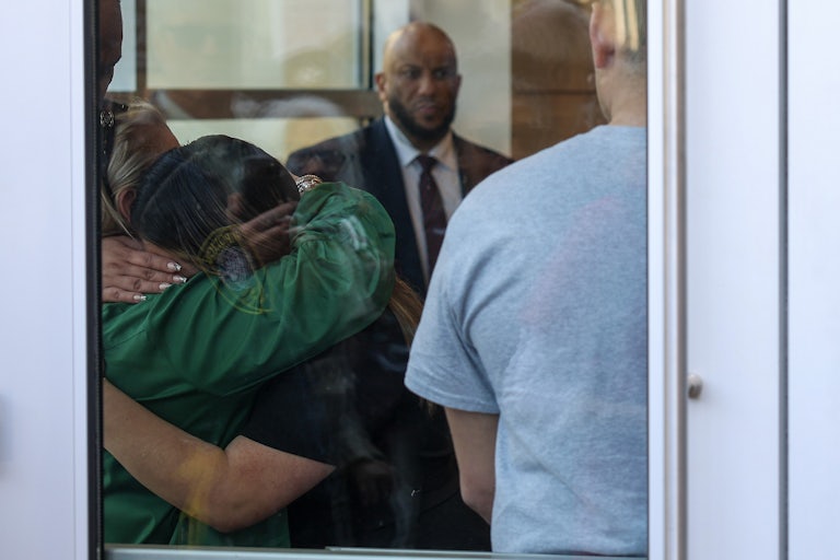 Jennifer Vasquez Sura, the wife of Kilmar Abrego Garcia, hugs their family pastor. The photo is taken through a window.