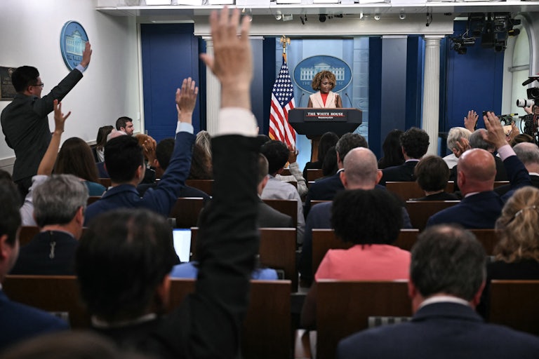 Reporters raise their hands during a briefing with Karine Jean-Pierre