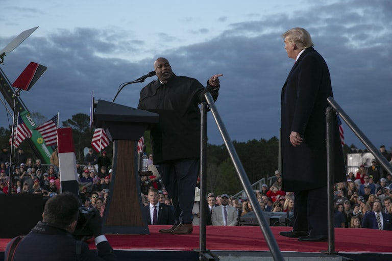 Mark Robinson points at Donald Trump as they stand onstage together at a rally