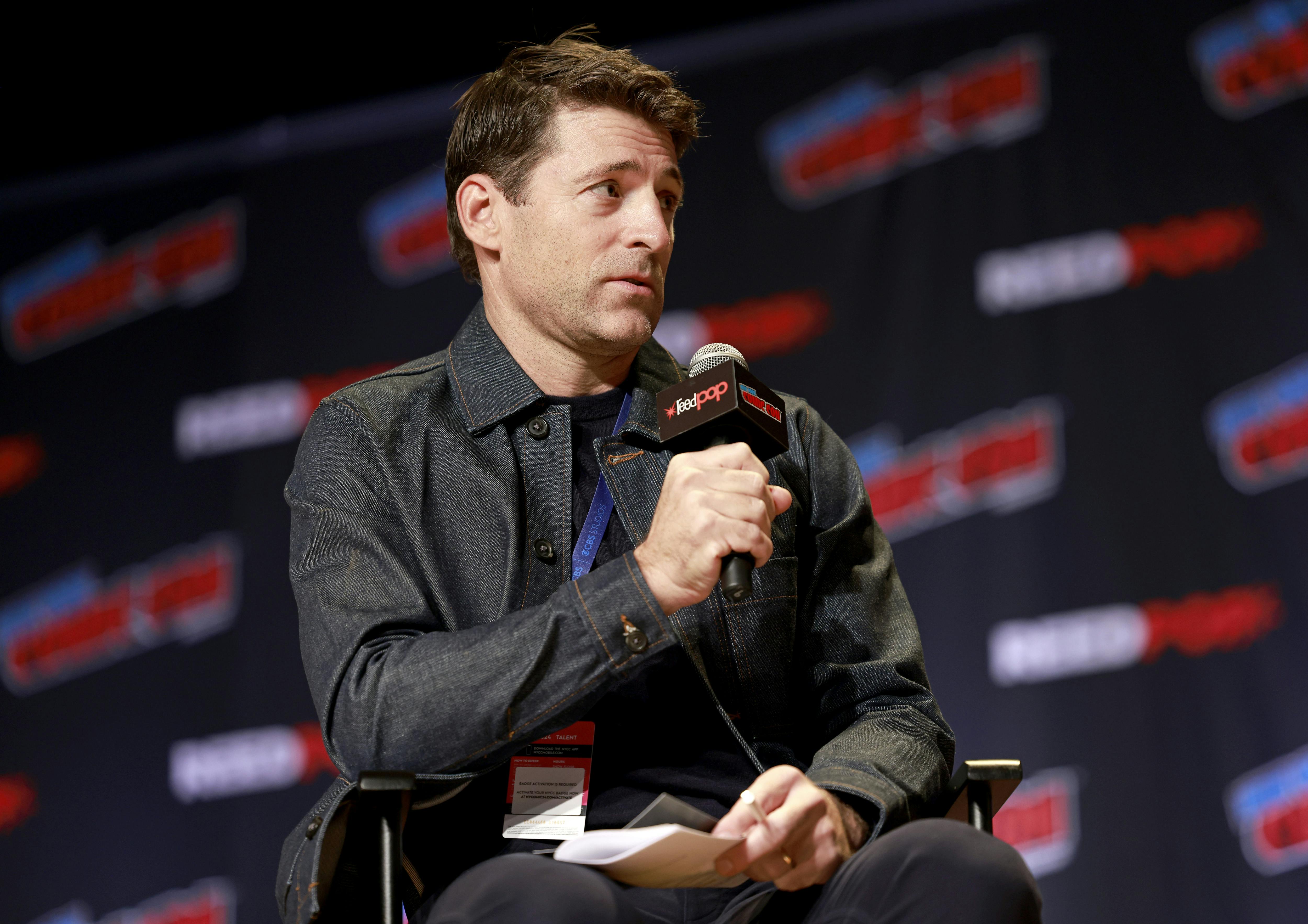 News anchor Tony Dokoupil speaks into a microphone while sitting in a chair