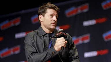 News anchor Tony Dokoupil speaks into a microphone while sitting in a chair