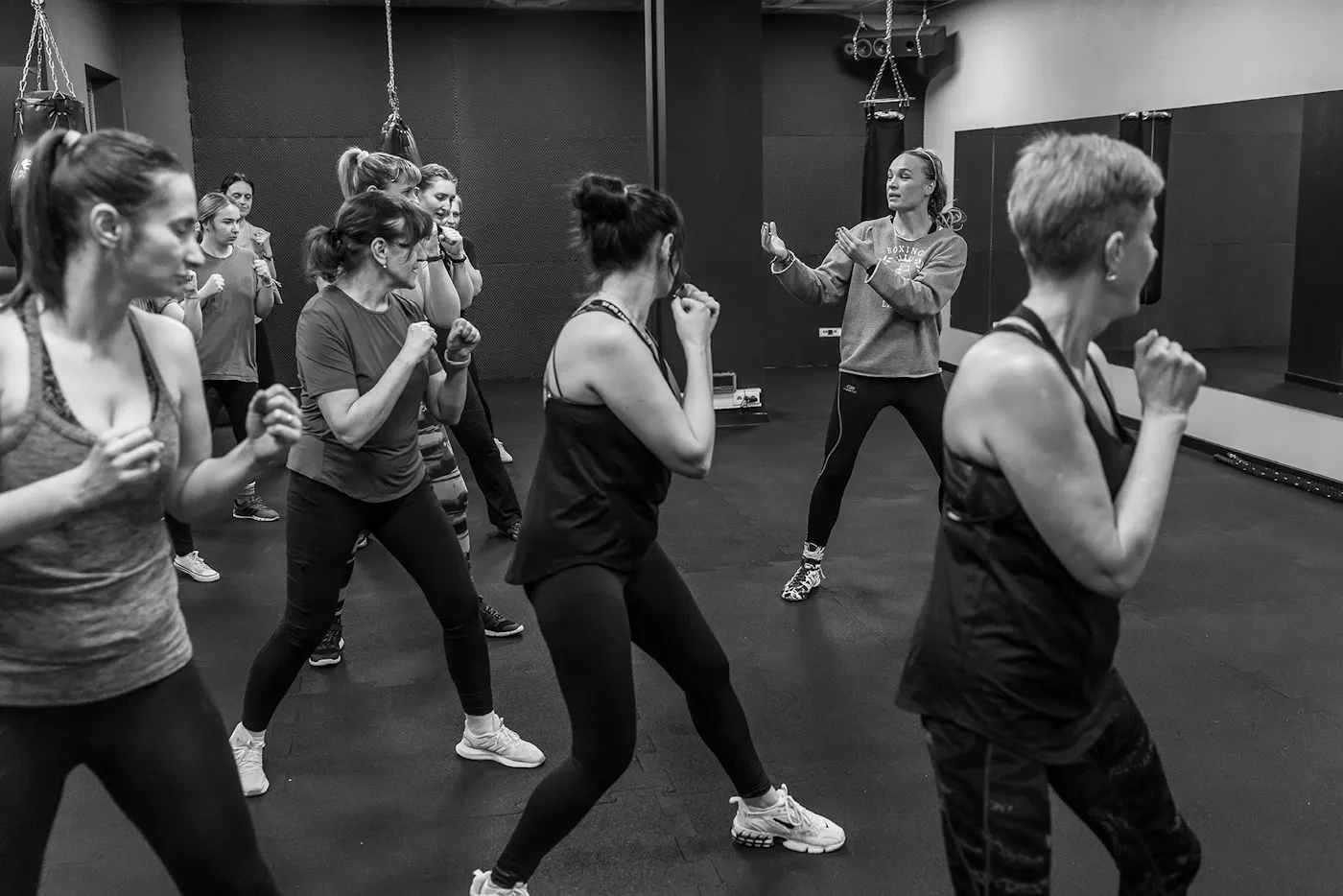 A black and white photograph of Aleksandra Sidorenko, a Ukrainian-born Polish professional boxer and European lightweight boxing champion, leading a class of Ukrainian women refugees in Warsaw.