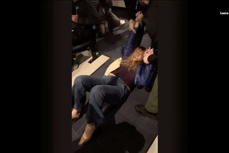 A woman is on the ground being dragged by two men