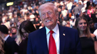 Donald Trump smiles (or possibly grimaces) while standing at a UFC match in Miami