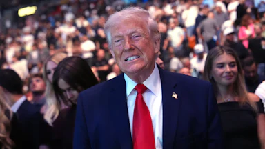 Donald Trump smiles (or possibly grimaces) while standing at a UFC match in Miami