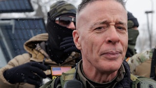 CBP Commander Gregory Bovino stands with masked federal immigration agents outside a gas station in Minneapolis, Minnesota