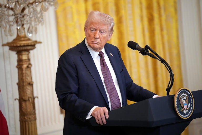 Donald Trump looks to the side as he stands at the presidential podium in the White House.