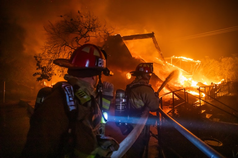 Firefighters fight the flames from the Palisades Fire