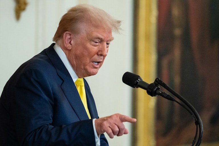 Donald Trump, hunched over, points while speaking at the presidential podium.