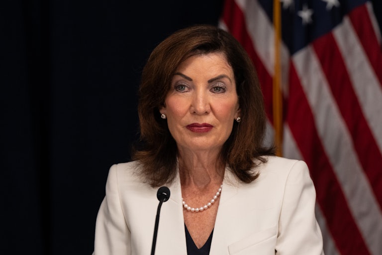 New York Governor Kathy Hochul sits in front of a microphone