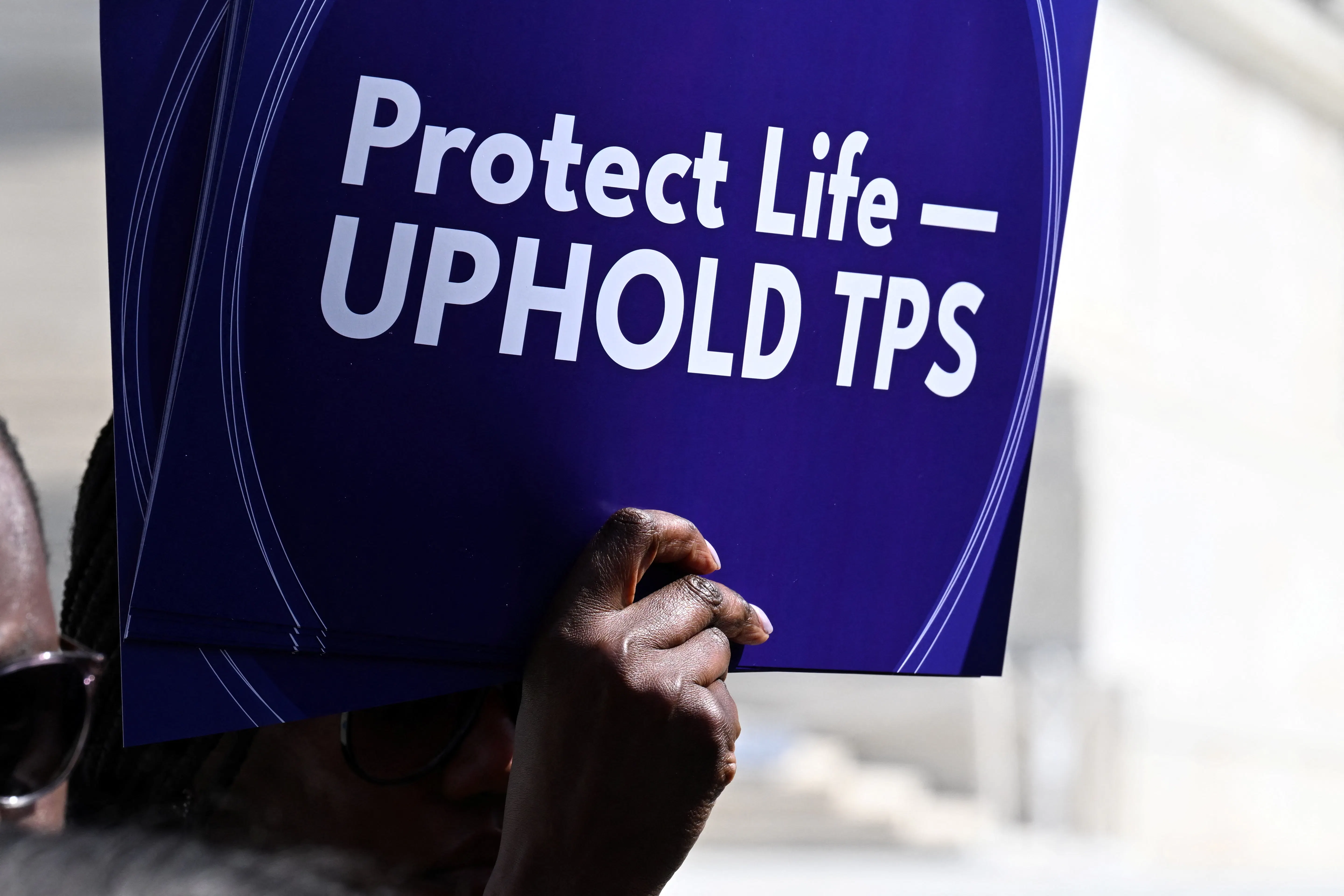 A person holds up a sign that says, "Protect life—uphold TPS" at a protest outside the Supreme Court