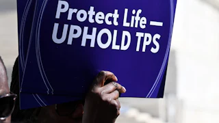 A person holds up a sign that says, "Protect life—uphold TPS" at a protest outside the Supreme Court