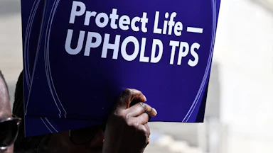 A person holds up a sign that says, "Protect life—uphold TPS" at a protest outside the Supreme Court