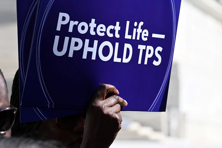 A person holds up a sign that says, "Protect life—uphold TPS" at a protest outside the Supreme Court