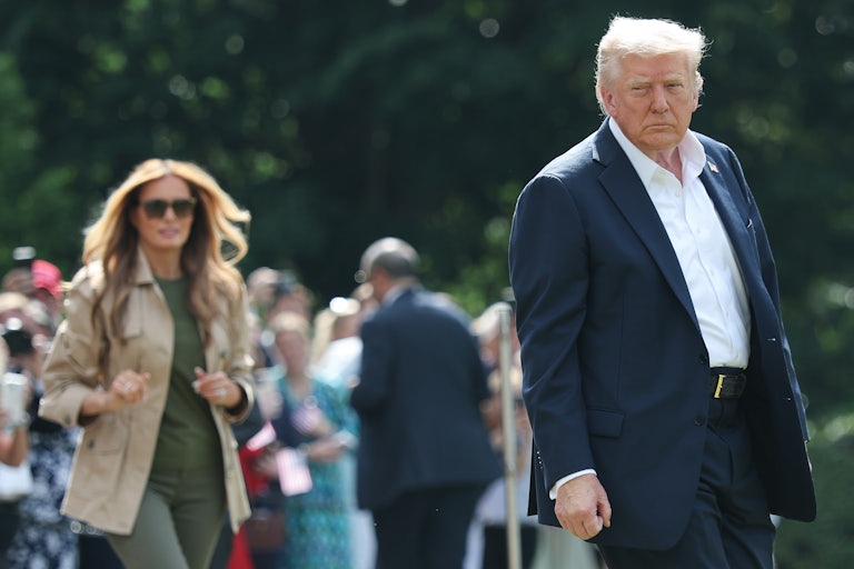 Donald Trump looks menacingly at the camera while his wife Melania walks behind him.