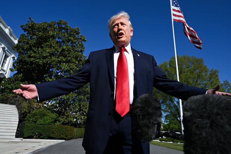 Donald Trump holds his arms out to the side and speaks while standing outside the White House