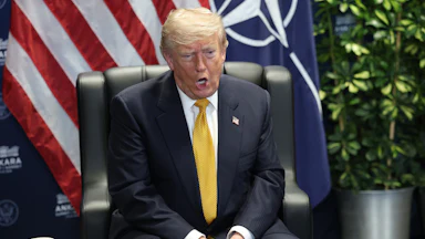 Donald Trump speaks while sitting in a chair