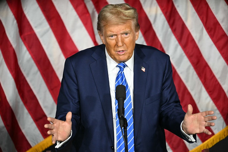 Donald Trump gestures while speaking into a microphone