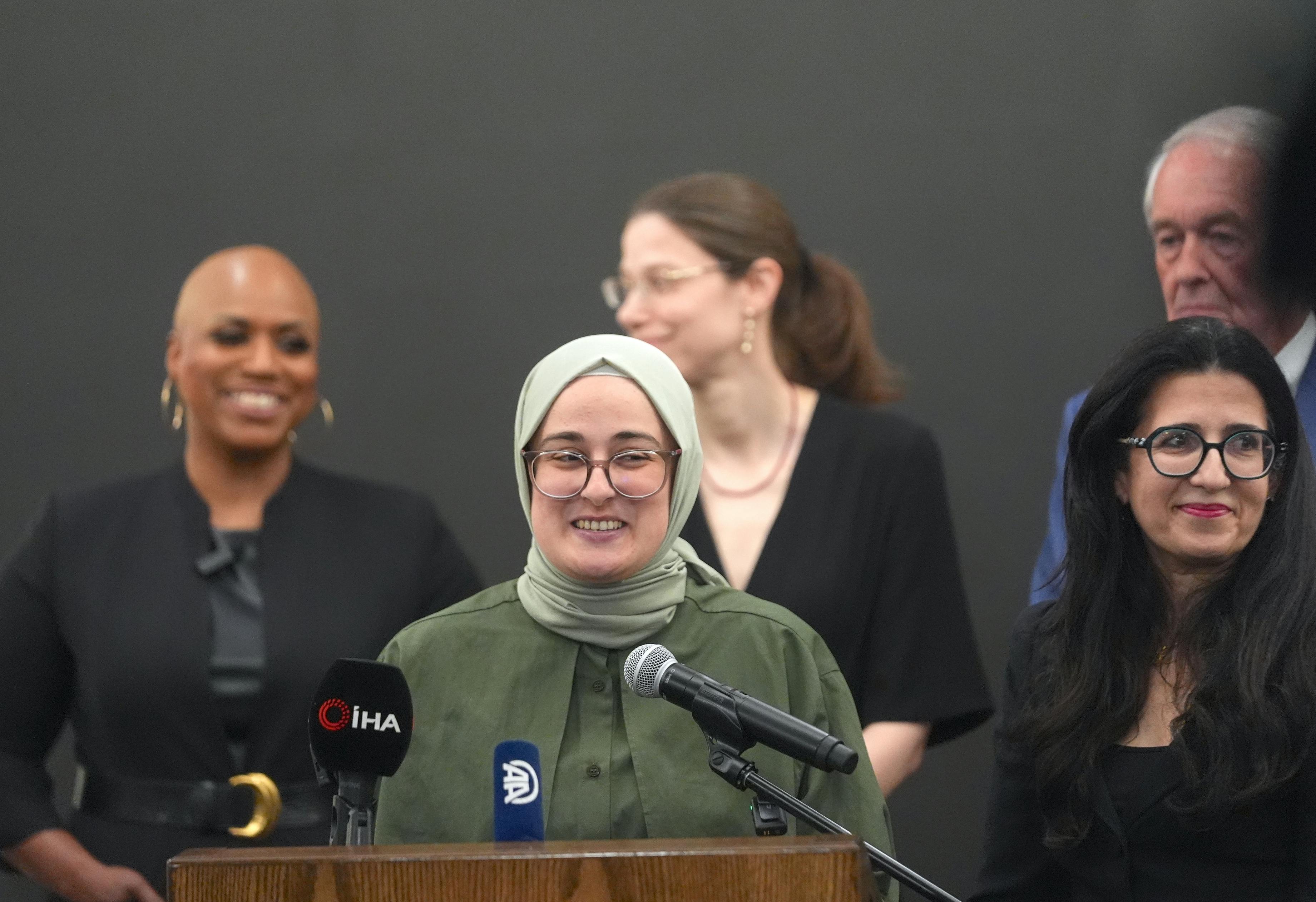 Tufts University grad student Rumeysa Ozturk speaks into microphones at a podium