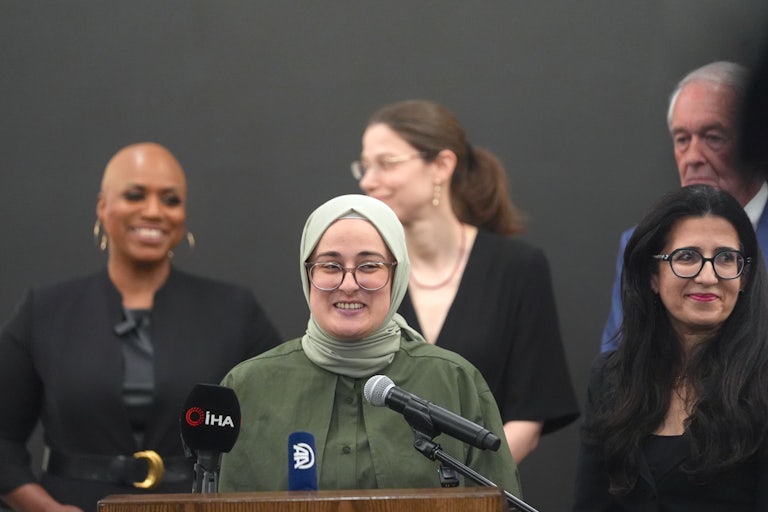 Tufts University grad student Rumeysa Ozturk speaks into microphones at a podium