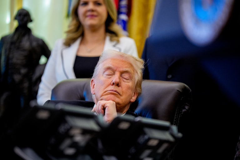 Donald Trump sits at his desk in the Oval Office with his eyes closed
