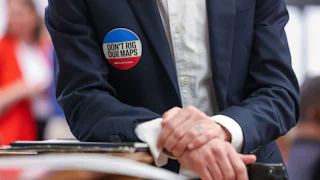 An attendee wears a “Don’t Rig Our Maps” sticker during a meeting in the Blatt Building at the South Carolina State Capitol in Columbia, South Carolina on Friday, May 8, 2026.