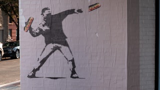 A Bansky-like mural of the D.C. sandwich guy throwing a sandwich while wearing a face mask and a backwards cap.