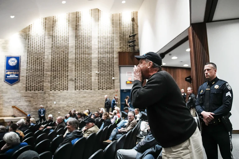 A man cups his hand as he stands and yells in Representative Mike Lawler's town hall.