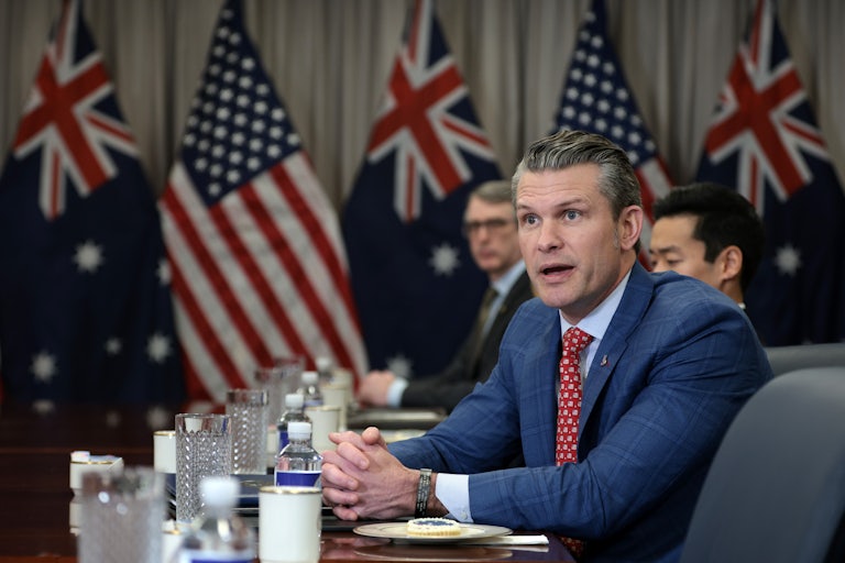 Defense Secretary Pete Hegseth speaks to members of the press while seated at a table with Australian officials. (The U.S. and Australian flags can be seen in the background.)