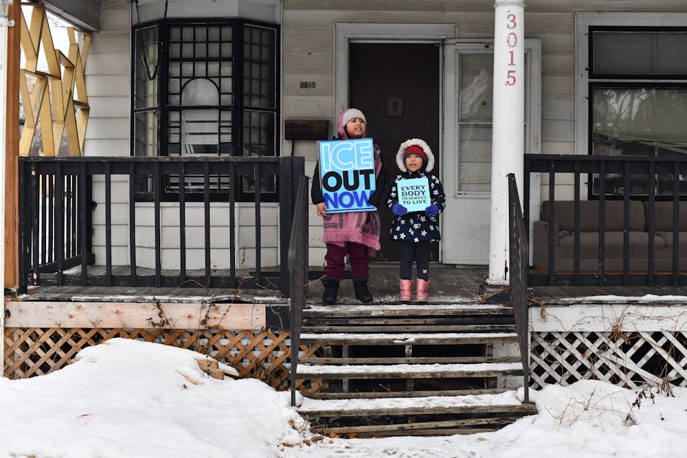 Children hold signs on the stoop of a house as protesters march from Powderhorn Park in Minneapolis against Immigration and Customs Enforcement and the fatal shooting of Renee Good.