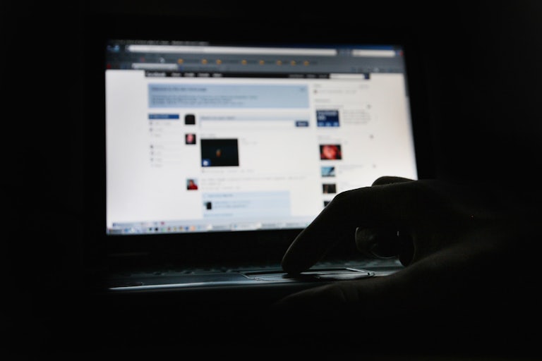 A user scrolls through Facebook on a laptop.