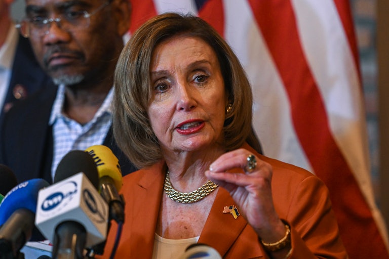 Nancy Pelosi speaking in front of several mics