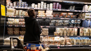 A woman shops in the dairy aisle of a grocery store